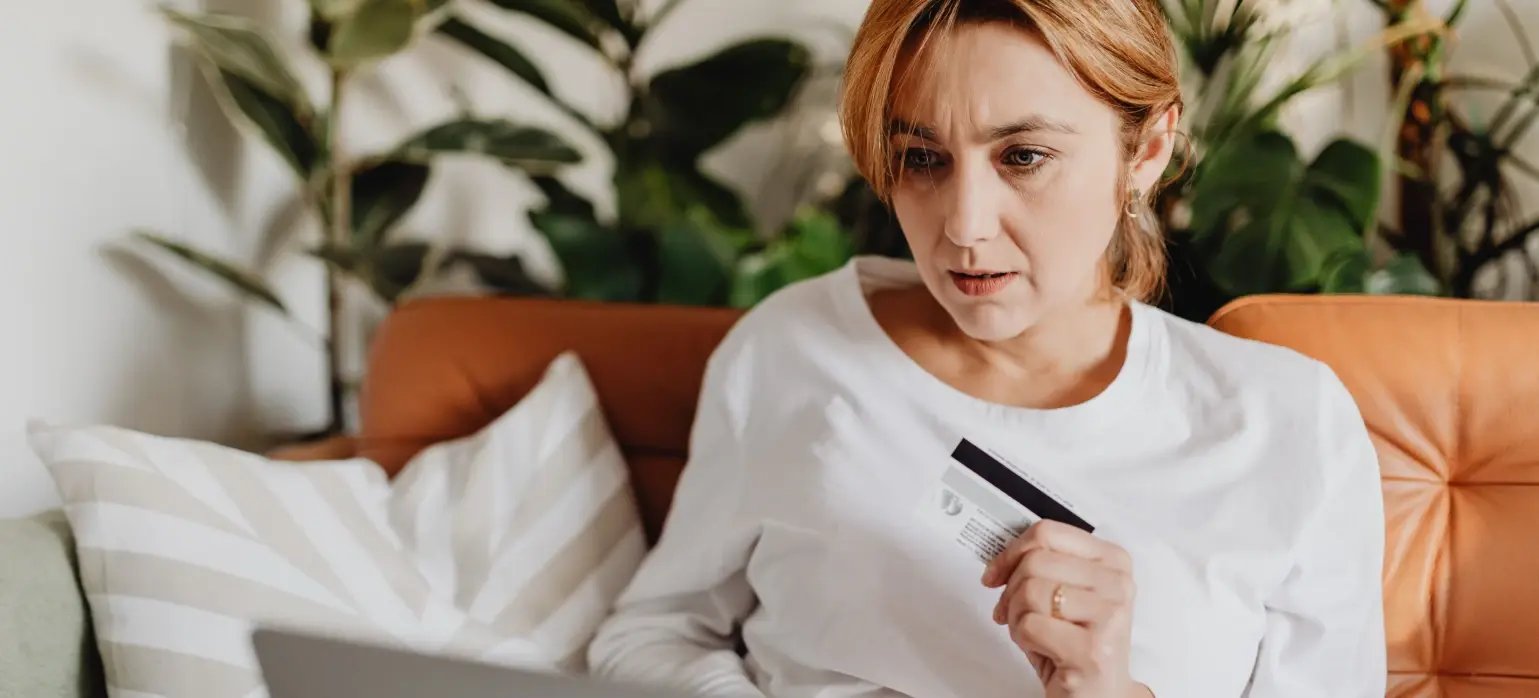 Femme avec une carte bleu dans la main, en fin de parcours d'achat en ligne.